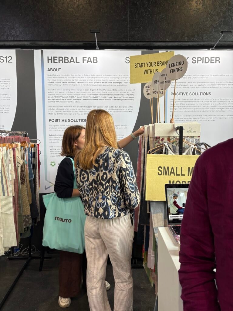 Buyers exploring eco-friendly textile samples at the Herbal Fab booth during a sustainable fashion and fabric exhibition