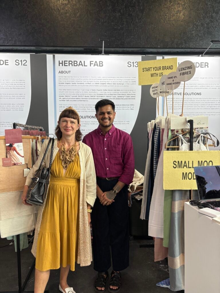 Herbal Fab team member with a visitor at a sustainable textile exhibition booth showcasing eco-friendly fabric collections