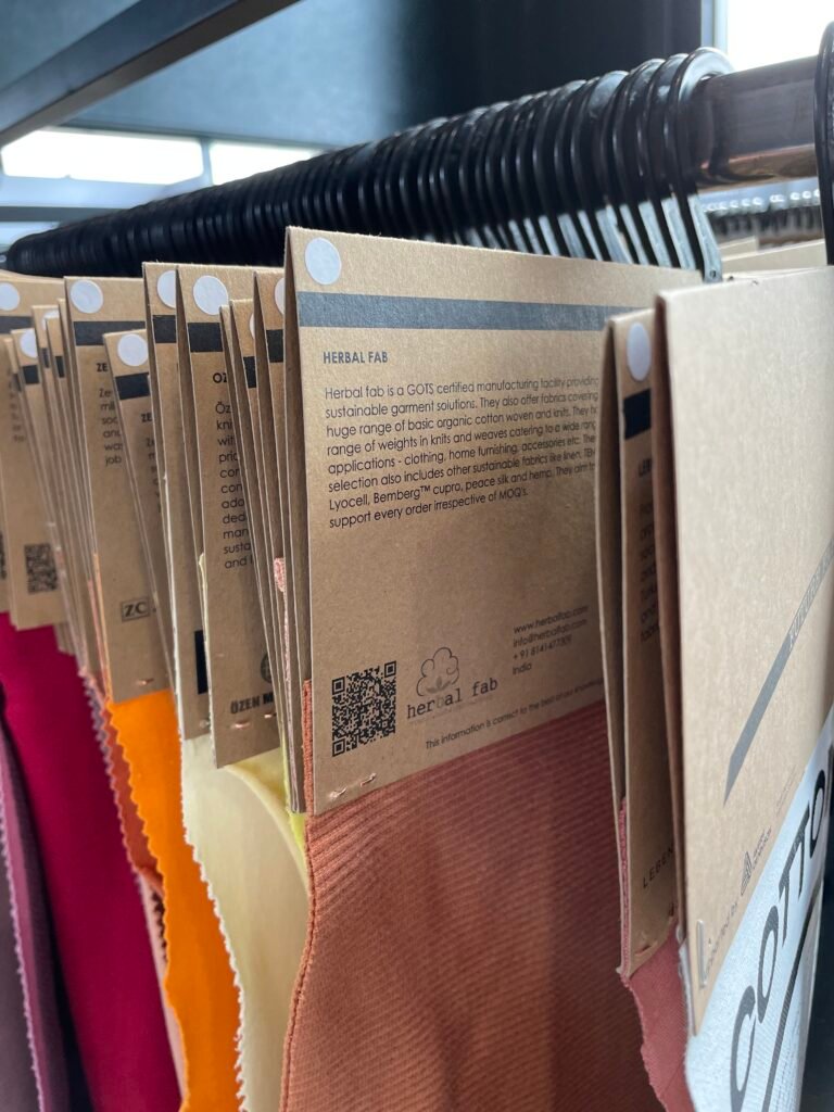 Organic fabric swatches displayed at a textile exhibition showcasing sustainable materials and GOTS-certified fabric collections