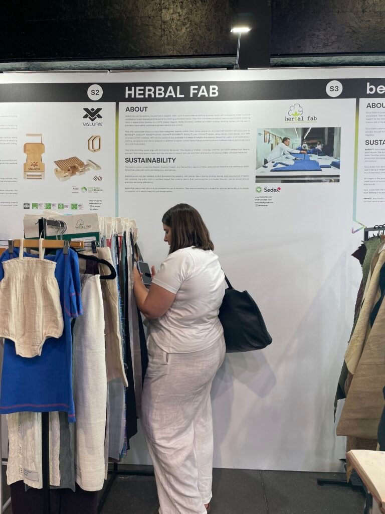 Visitor exploring Herbal Fab’s sustainable fabric swatches and eco-friendly textile collections at an international fashion expo