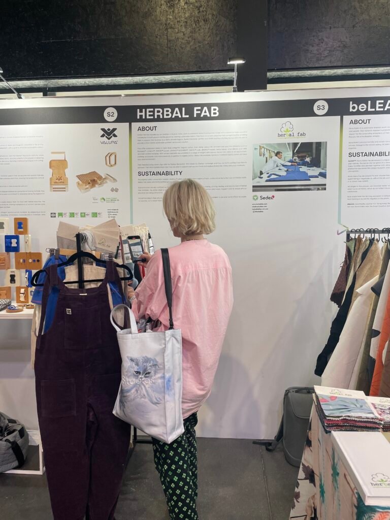 Visitor exploring the Herbal Fab sustainable textile display at a fabric and fashion trade exhibition
