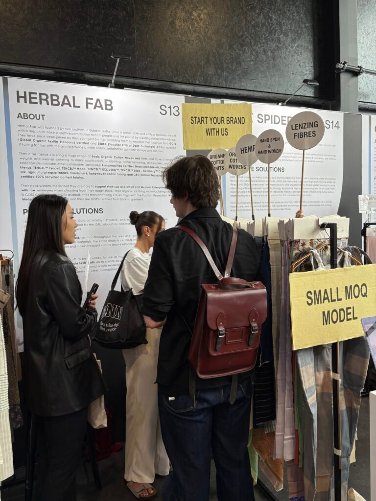 Visitors exploring Herbal Fab’s sustainable textile booth featuring organic fabrics and eco-friendly material collections at a trade expo