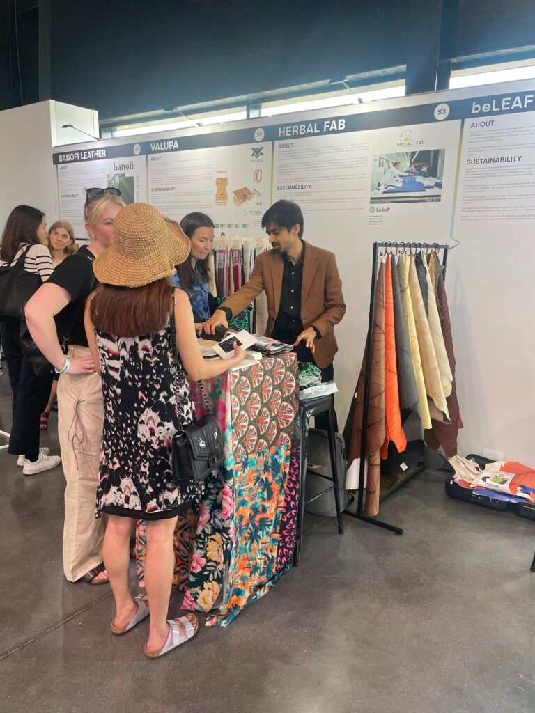 Visitors interacting at the Herbal Fab sustainable textile exhibition booth showcasing eco-friendly fabrics and ethical textile solutions